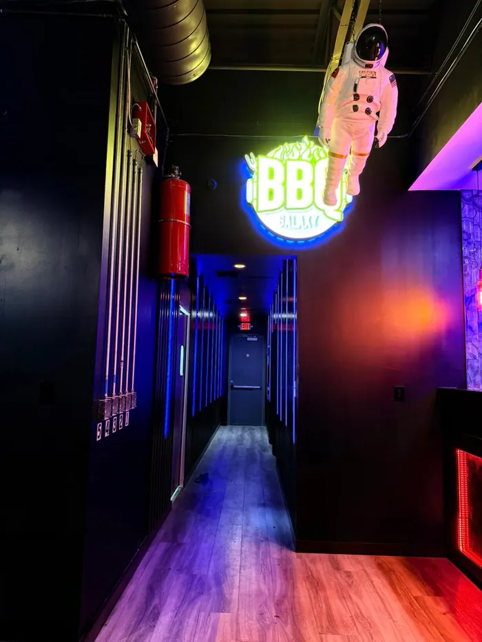 Neon BBQ Galaxy sign and suspended astronaut above the entry corridor